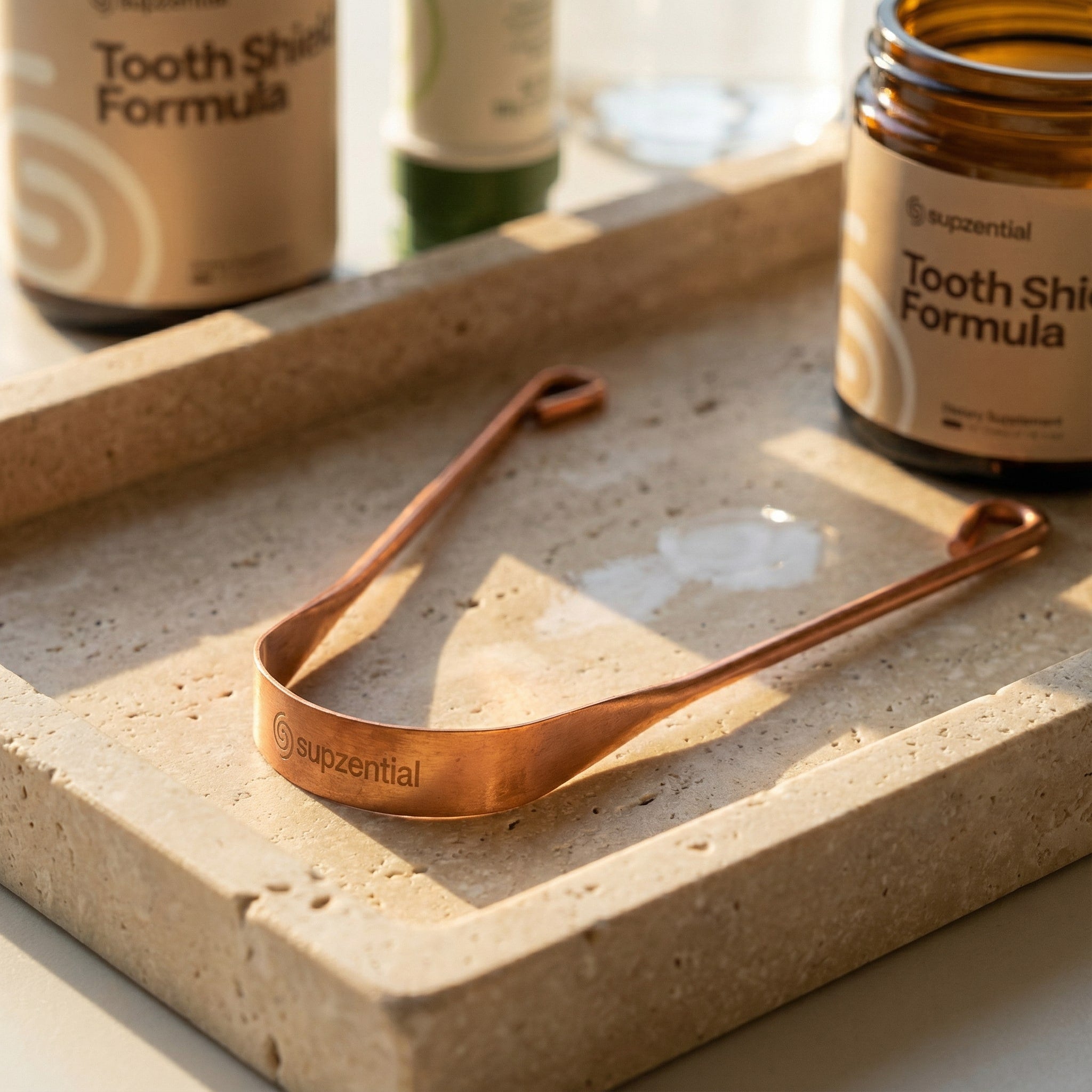 A Copper Tongue Scraper rests on a stone tray, highlighting a key step in a premium oral hygiene routine.