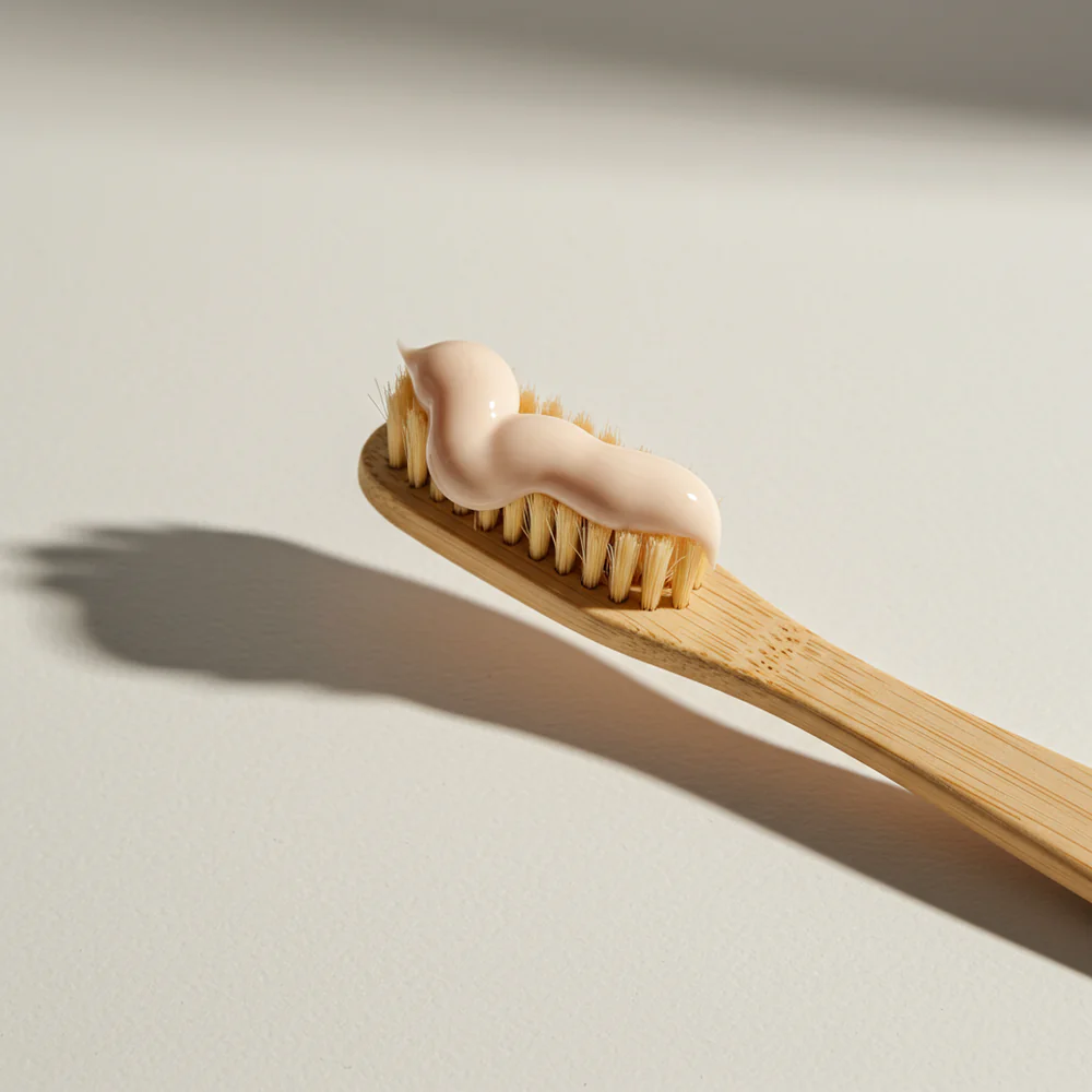 A smooth swirl of Supzential More than a Toothpaste sits on a wooden toothbrush, ready for a clean and refreshing experience.