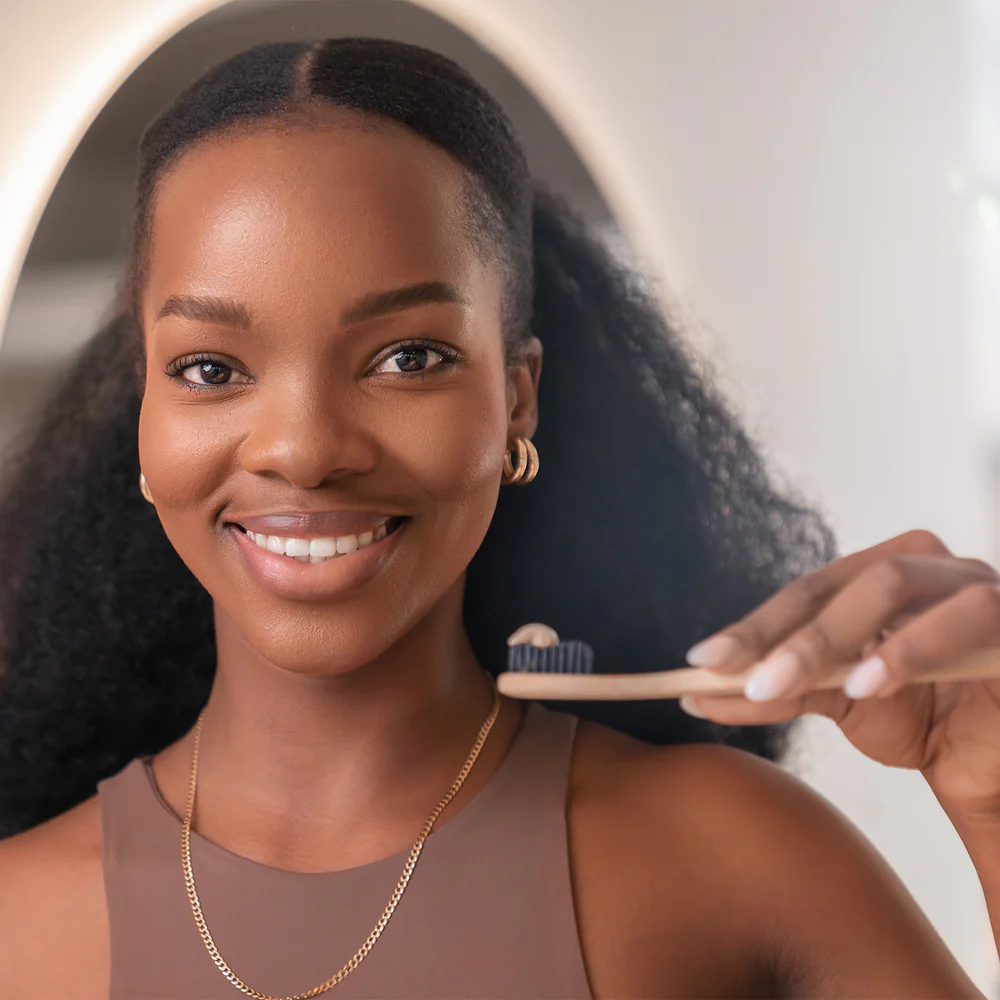A woman smiles radiantly while holding a wooden toothbrush, highlighting the confidence of a Supzential smile.