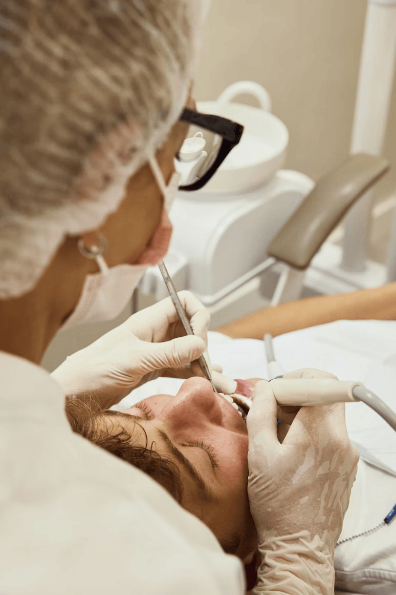 Dental procedure being performed on a patient with dental tools and equipment in the background.